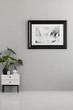 © Photographee.eu - Plant on white cabinet in empty grey apartment interior with poster. Real photo. Place for your sofa