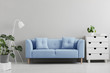 © Photographee.eu - Blue sofa between white lamp and cabinet in grey living room interior with plants. Real photo
