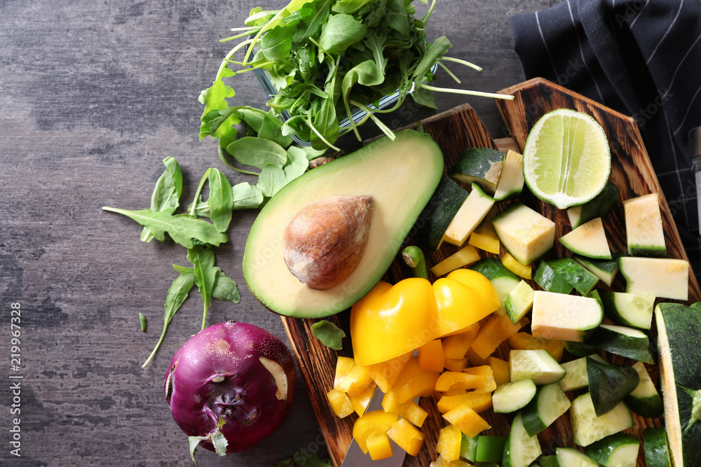 Board with ingredients for tasty vegetable salad on grey table