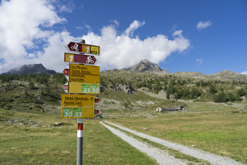 Wall Mural - Pontresina, Graubünden, Switzerland, 09-11-2018,Hiking and mountaibiking signpost at the Bernina Express trail on Bernina Pass, near Pontresina, Engadin, Swiss alps