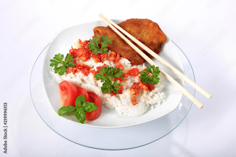 Ryż na białym talerzu z kotletem schabowym, sosem, pomidorem, zieloną petruszką i bazylią. - obrazy, fototapety, plakaty 