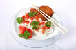 Ryż na białym talerzu z kotletem schabowym, sosem, pomidorem, zieloną petruszką i bazylią.