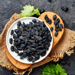 Poster - Black raisins on plate. Top view of dried grapes.