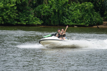 Happy young couple with thumbs up enjoying and having fun riding on a jet ski. Tropical coast of Sri Lanka