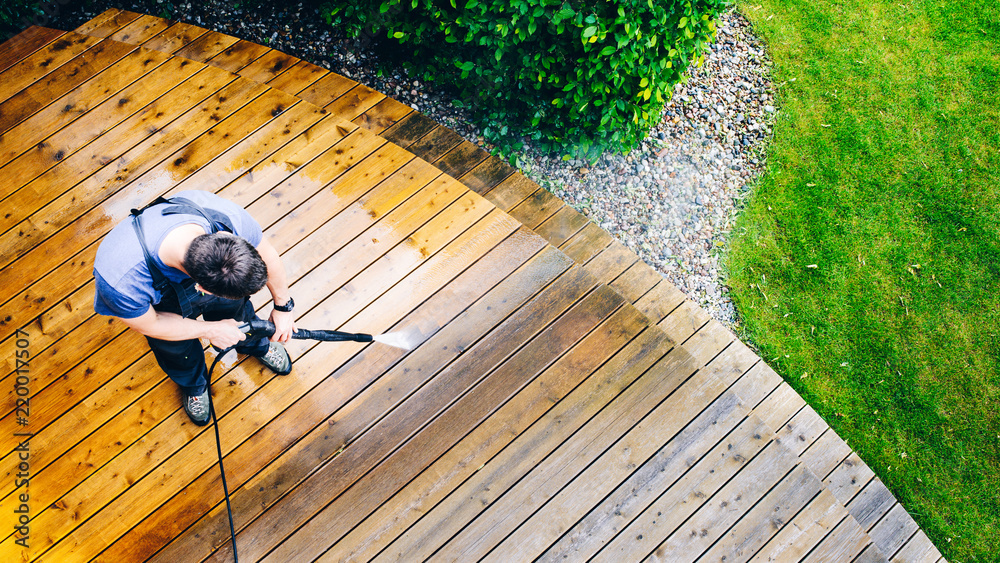 man cleaning terrace with a power washer - high water pressure cleaner on wooden terrace surface - obrazy, fototapety, plakaty 