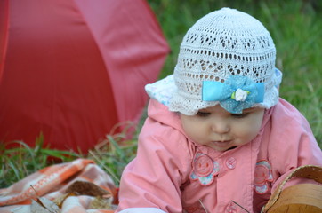 Portrait of happy little baby girl playing at natural outdoors park background. baby girl in autumn park in pink raincoat with red umbrella.