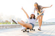 © opolja - Two smiling young girls having fun while riding on a skateboard at the park.