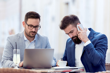 Two young businessman talking in cafe