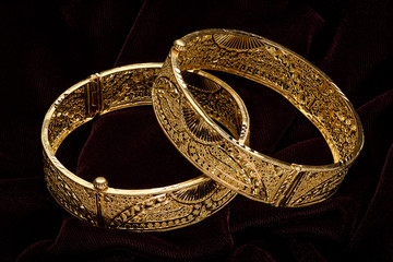 Golden bracelet on a dark pattern
