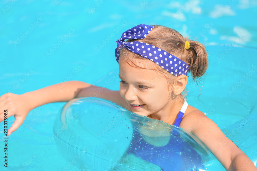 Cute girl swimming in pool on summer day