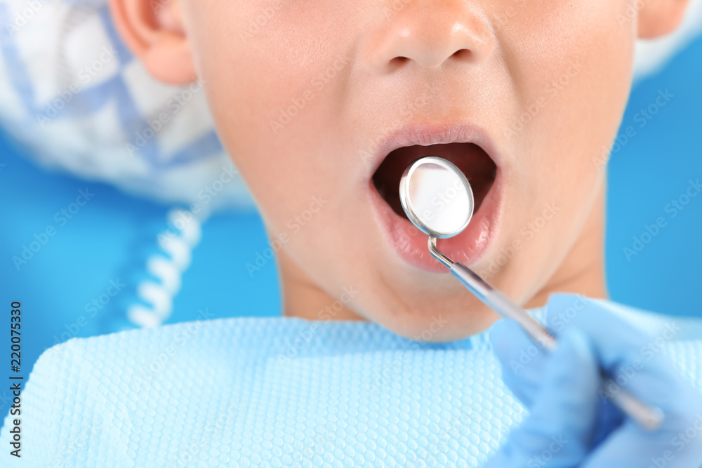 Dentist examining little boy's teeth in clinic, closeup