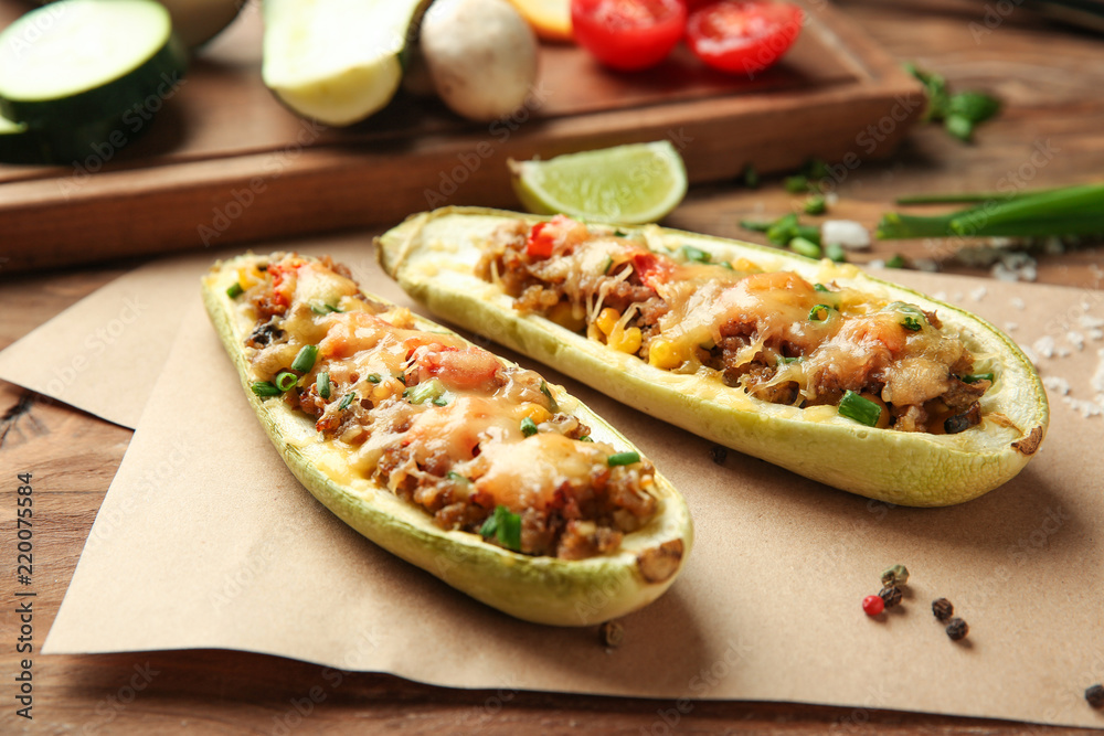 Meat stuffed zucchini boats on wooden table, closeup