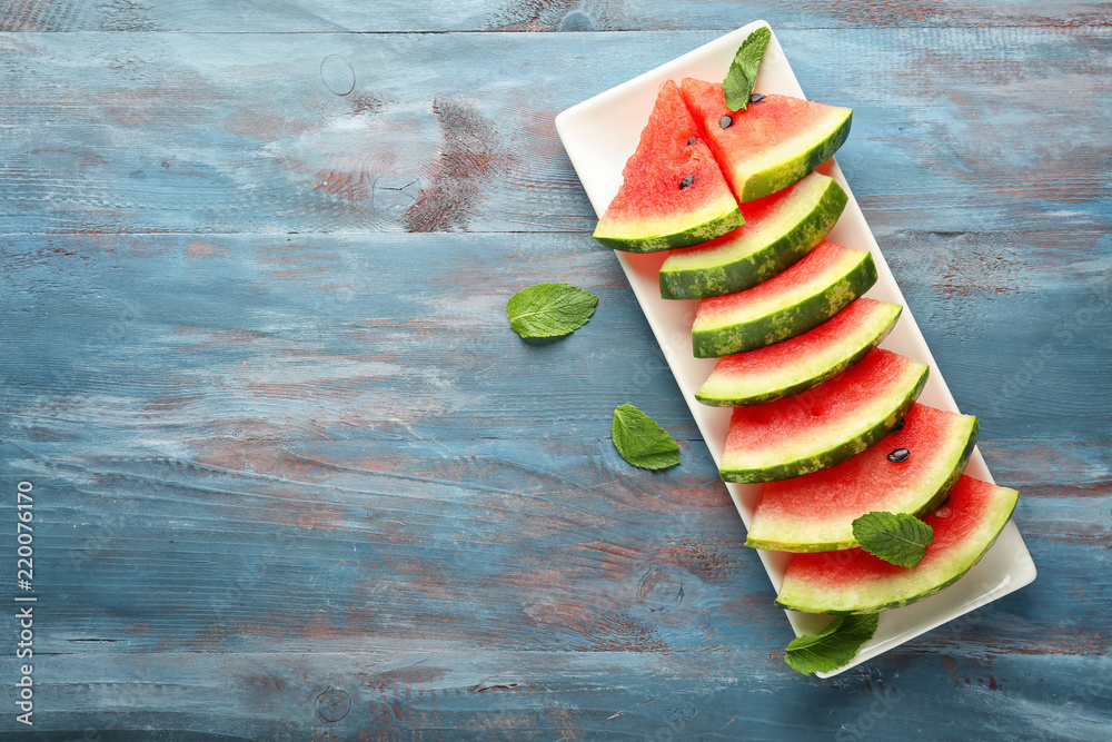 Plate with delicious sliced watermelon on wooden background