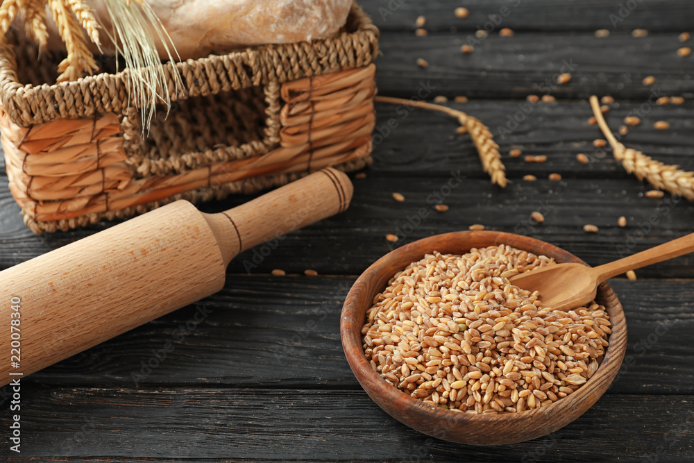 Bowl with wheat grains on wooden background