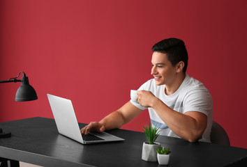 Young freelancer drinking coffee and working on laptop at home