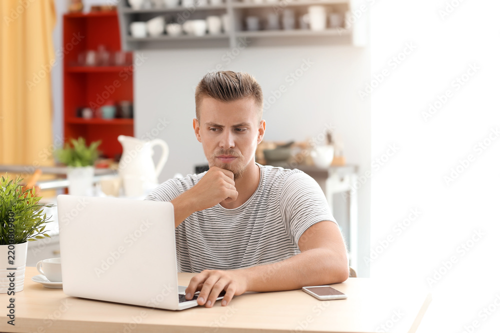 Emotional freelancer working on laptop in kitchen