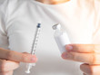 Close up of diabetes patient in white T-shirt holding blank label insulin vial and plastic syringe for prepare a self-injection at home. Health care and medical concept. World diabetes day.