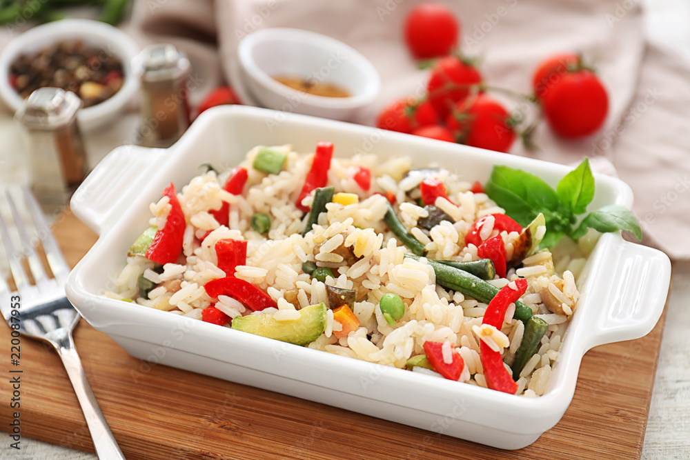 Dish with tasty boiled rice and vegetables on wooden board