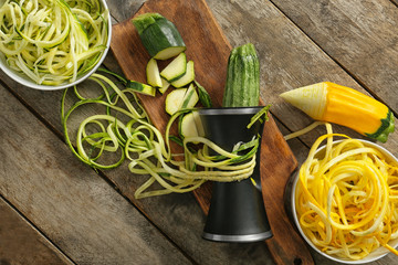 Fresh zucchini spaghetti with spiral grater on wooden table