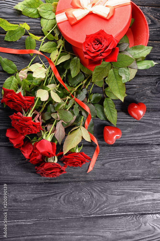 Beautiful red roses and gift box on wooden background