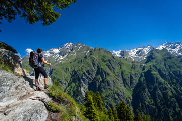 female traveler with backpack hiking mountain trail and admiring views of swiss alps in val de bagne