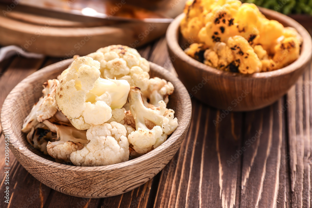 Bowls with colorful cauliflowers on wooden table