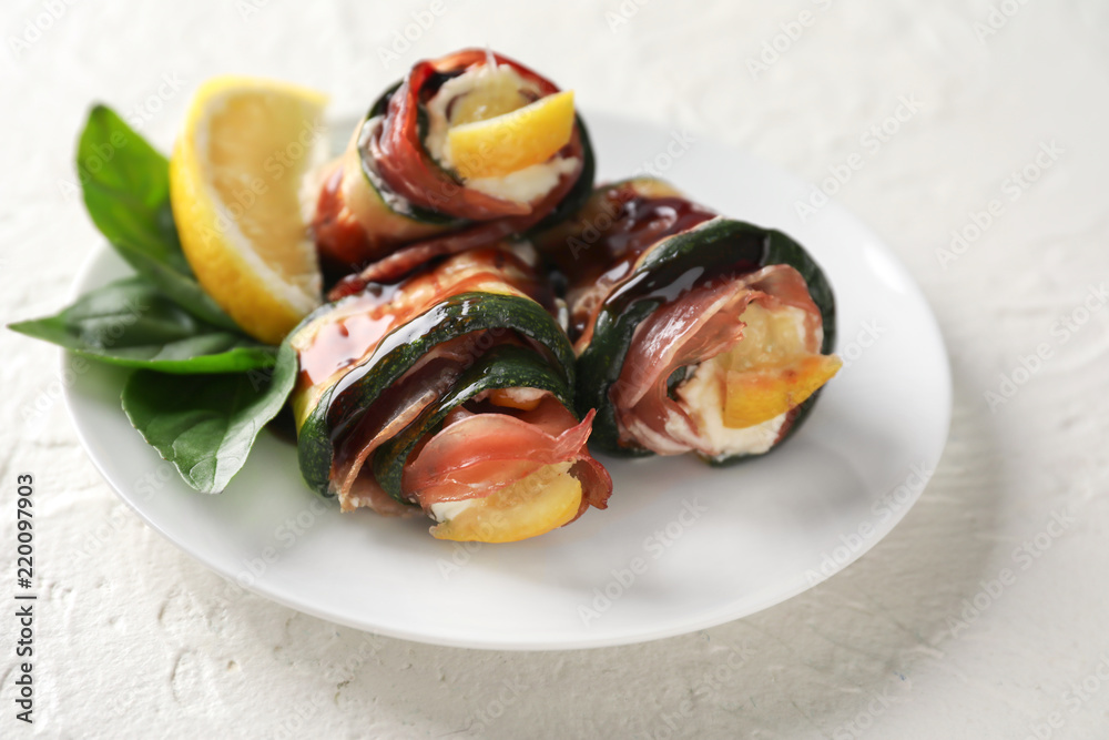 Plate with tasty zucchini rolls on white table
