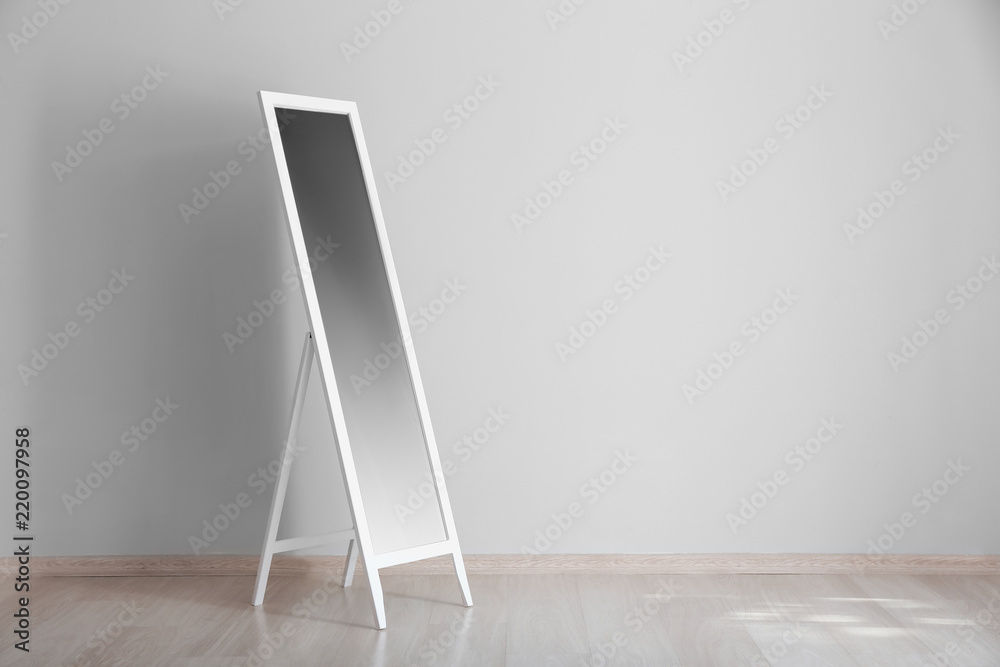 Big stylish mirror near light wall in empty room
