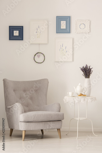 Grey Armchair Standing Next To Metal End Table With Jug And
