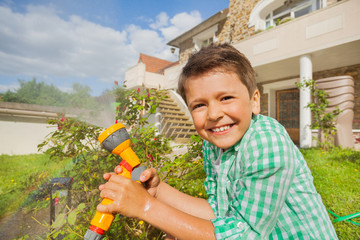 Wall Mural - Happy boy watering garden with hand sprinkler