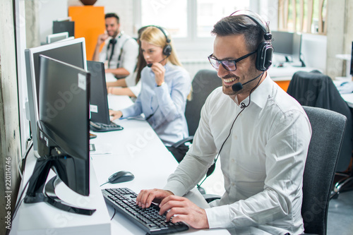 Fotomural Young male technical support dispatcher with headset talking with customer in ca