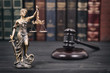 Judge Gavel and Lady Justice on a black wooden background.