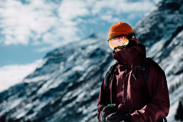Wall Mural - skiier with googles standing in alp environment with mountain all around him in sunny weather