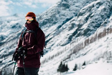 Wall Mural - skiier with googles standing in alp environment with mountain all around him in sunny weather