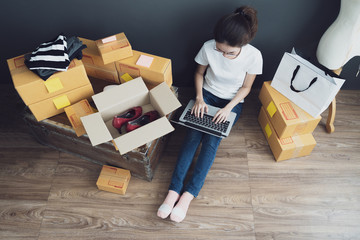 Top view of women working laptop computer from home on wooden floor with postal parcel, Selling online ideas concept