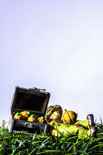 Fotografie, Obraz vertical of scarecrow figurine laying in green grass against wood chest full of