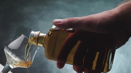 Poster - Pouring Glass of alcohol on a dark background, rotation 360 degrees.