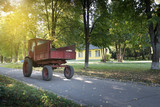 Fototapeta Sypialnia - Vintage red tractor at the asphalt road with trees