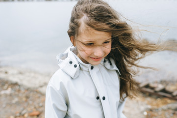 portrait  of a smilling girl near the sea in the raincoat