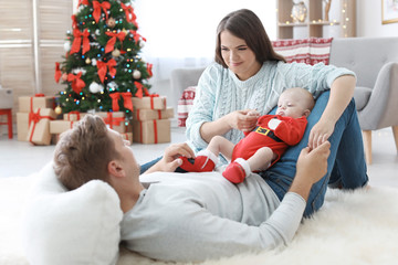 Wall Mural - Happy couple with baby celebrating Christmas together at home