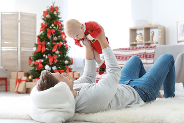 Wall Mural - Young man with baby in Christmas suit at home