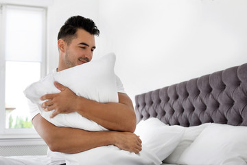 Wall Mural - Young man with soft pillow on bed at home