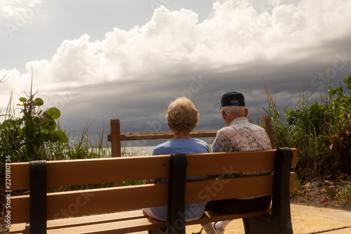 Fotografia, Obraz An elderly couple enjoying a view of the ocean with a storm rolling in