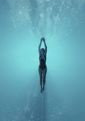 Wall Mural - Woman swimming underwater in a sea.