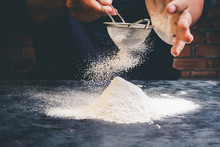 Chef Sifting Flour On Black Table