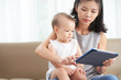 © DragonImages - Young Asian woman showing application on tablet computer to her little daughter