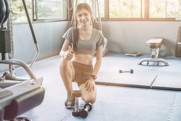 young asian pretty woman doing exercises with dumbbell at biceps in fitness gym