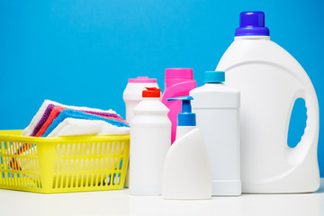 Wall Mural - Photo bottles of cleaning products and multi-colored towels in basket isolated on blue background