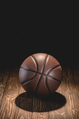 one rubber basketball ball on wooden floor in dark room