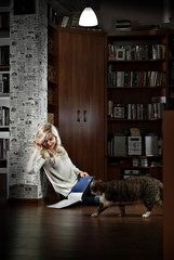 Wall Mural - Beautiful girl reading a book in the library, next to the cat